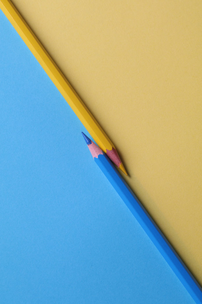2 Yellow and blue color pencils kept next to each other in opposite direction to depict thinking for product management. 